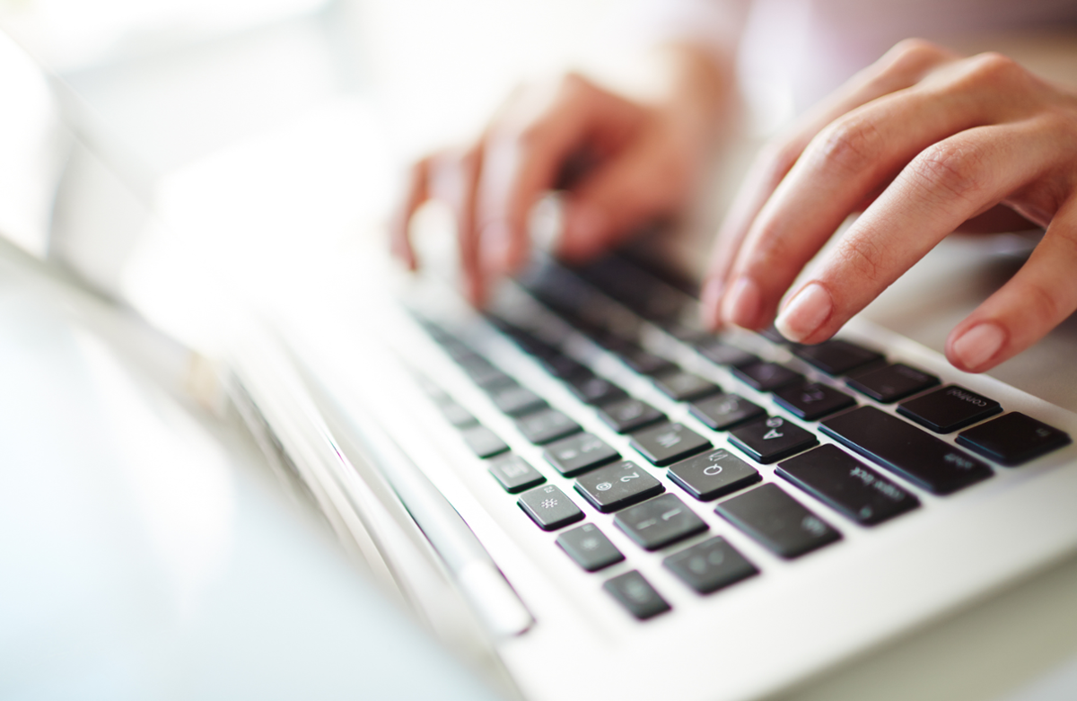 persoa tecleando no teclado dun ordenador portátil