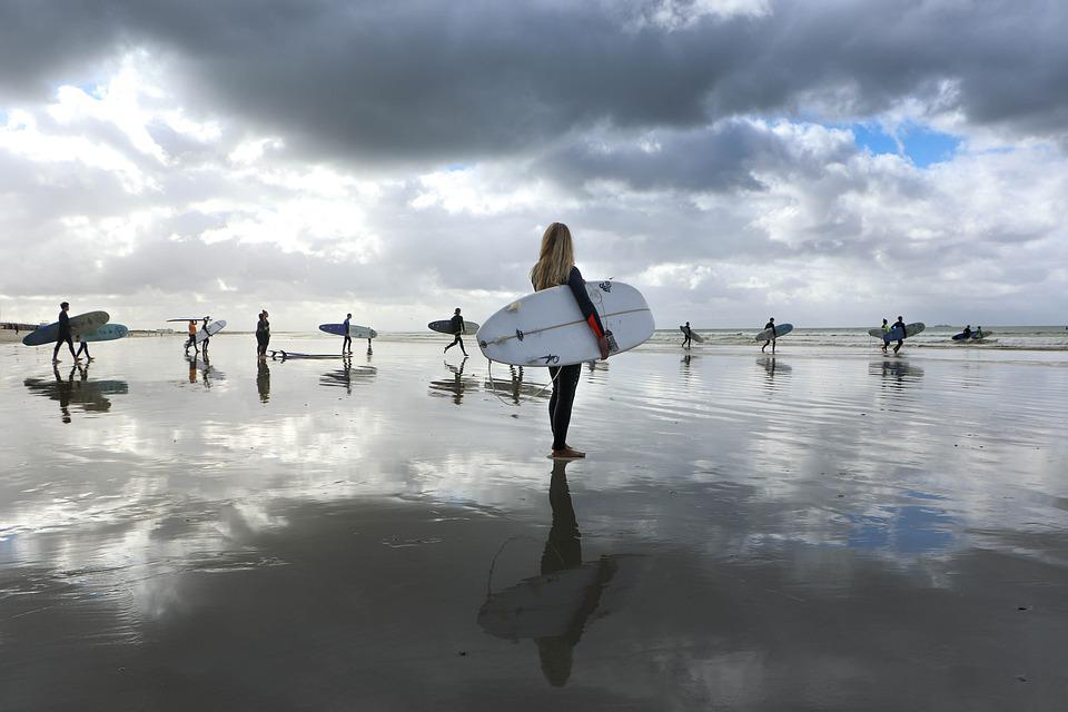 Persoas con taboas de surf nunha praia.